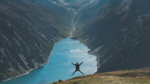 Person Bouncing Back Jumping on a Cliff Near a Lake